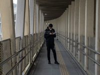 A man wearing a face mask looks at his phone while standing on a footbridge on December 29, 2022 in Macau, China. (