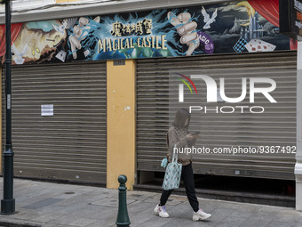 A woman wearing a face mask walks pass a closed store on December 29, 2022 in Macau, China. (