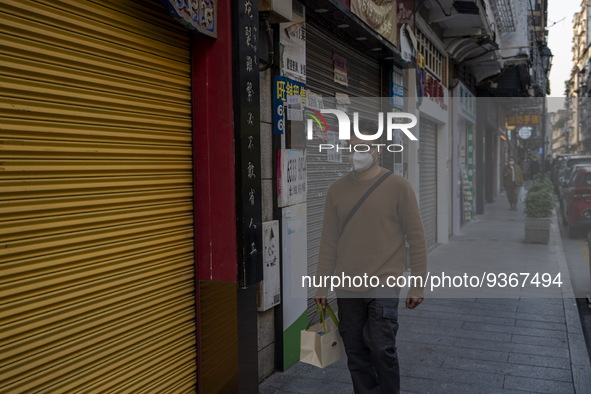 A man wearing a face mask walks pass closed stores on December 29, 2022 in Macau, China. 