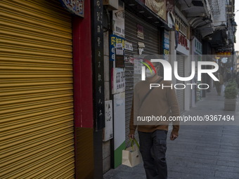 A man wearing a face mask walks pass closed stores on December 29, 2022 in Macau, China. (