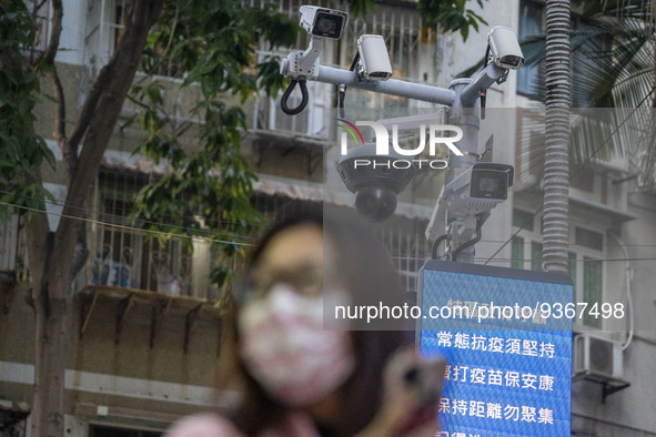 A women wearing face mask walks in front of a dozen of CCTV Camera on December 29, 2022 in Macau, China. 