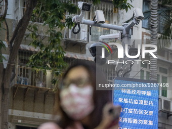 A women wearing face mask walks in front of a dozen of CCTV Camera on December 29, 2022 in Macau, China. (