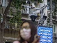 A women wearing face mask walks in front of a dozen of CCTV Camera on December 29, 2022 in Macau, China. (