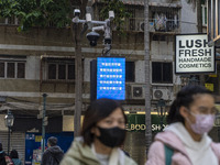 People wearing face masks in front of a dozen of CCTV Camera on December 29, 2022 in Macau, China. (