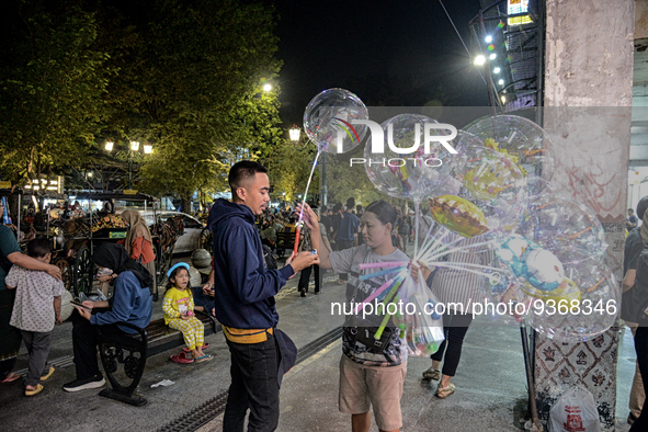 A man buys a ballons from a street vendor at Malioboro Street during holiday for the end of the year in Yogyakarta, Indonesia on December 30...