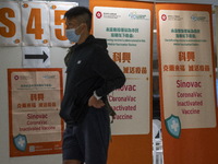 A man walks pass signs for the Sinovac CoronaVac Inactivated Vaccine by China Biotechnology company, Sinovac Biotech Ltd.,at a Covid-19 vacc...