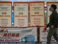 A man walks pass signs for the Sinovac CoronaVac Inactivated Vaccine by China Biotechnology company, Sinovac Biotech Ltd.,at a Covid-19 vacc...