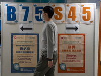 A man walks pass a sign for the Sinovac CoronaVac Inactivated Vaccine by China Biotechnology company, Sinovac Biotech Ltd. and a sign for th...