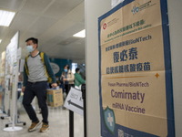 People walks pass a sign for the Comirnaty mRNA Vaccine by German biotechnology company BioNTech SE. at a Covid-19 vaccination station insid...