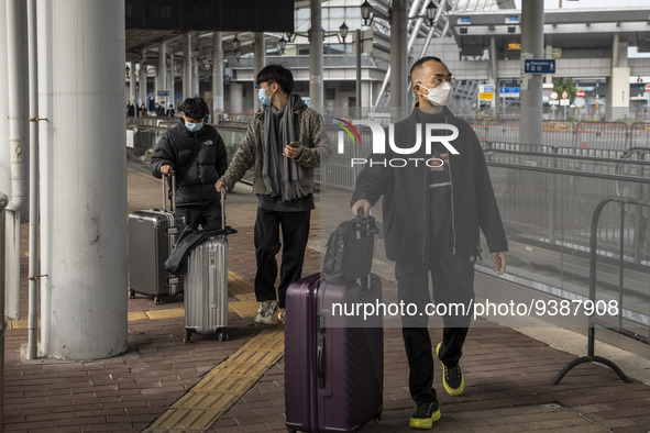 Travelers from China wearing face mask with luggages arrived in Shenzhen Bay Port on January 4, 2023 in Hong Kong, China. According to Local...