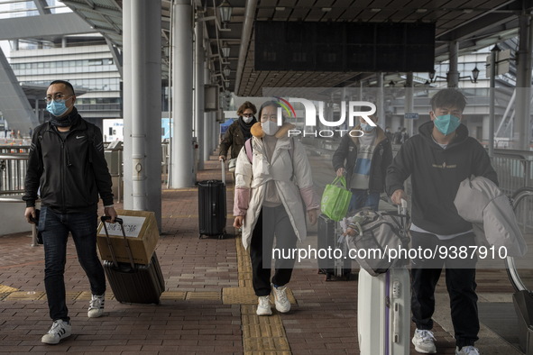 Travelers from China wearing face mask with luggages arrived in Shenzhen Bay Port on January 4, 2023 in Hong Kong, China. According to Local...