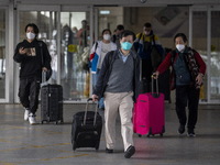 Travelers from China wearing face mask with luggages arrived in Shenzhen Bay Port on January 4, 2023 in Hong Kong, China. According to Local...