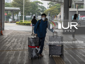 Travelers from China wearing face mask with luggages arrived in Shenzhen Bay Port on January 4, 2023 in Hong Kong, China. According to Local...