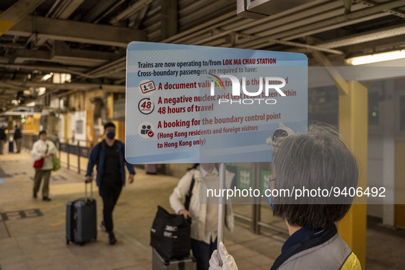 A worrier holding up a sign on requirement to cross at an MTR train platform for a train bound for Lok Ma Chau Control Point on January 8, 2...