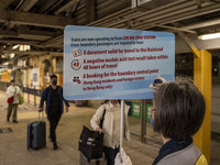 A worrier holding up a sign on requirement to cross at an MTR train platform for a train bound for Lok Ma Chau Control Point on January 8, 2...