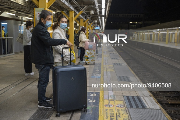 Commuters with suitcases waiting at an MTR train platform for a train bound for Lok Ma Chau Control Point on January 8, 2023 in Hong Kong, C...