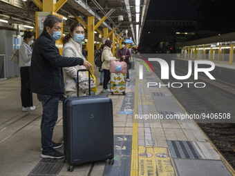 Commuters with suitcases waiting at an MTR train platform for a train bound for Lok Ma Chau Control Point on January 8, 2023 in Hong Kong, C...