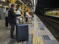 Commuters with suitcases waiting at an MTR train platform for a train bound for Lok Ma Chau Control Point on January 8, 2023 in Hong Kong, C...