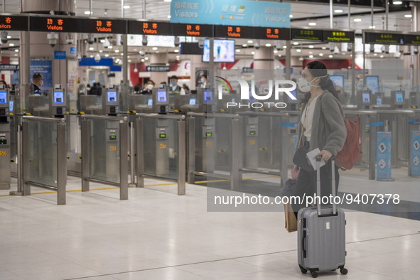 A women wearing a face mask with luggage walks pass automatic checkpoints at Lok Ma Chau Control Point on January 8, 2023 in Hong Kong, Chin...