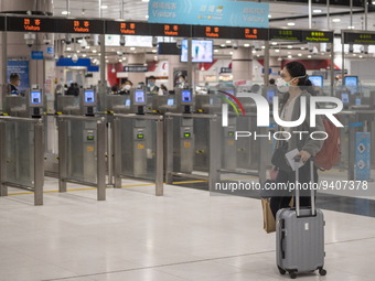 A women wearing a face mask with luggage walks pass automatic checkpoints at Lok Ma Chau Control Point on January 8, 2023 in Hong Kong, Chin...