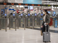 A women wearing a face mask with luggage walks pass automatic checkpoints at Lok Ma Chau Control Point on January 8, 2023 in Hong Kong, Chin...