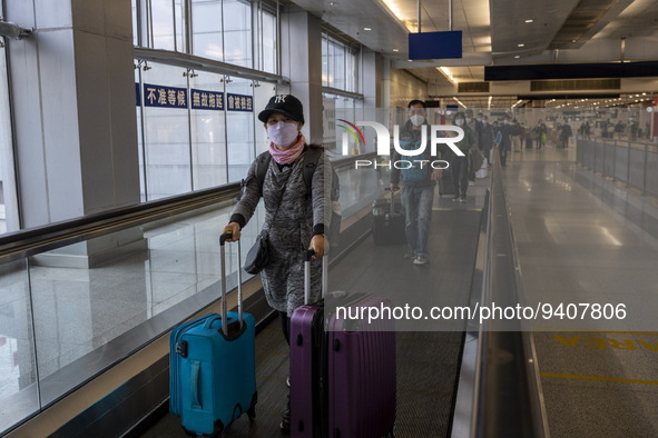 Travelers wearing face masks with suitcases crossing from Lok Ma Chau control point in Hong Kong to Futian Port in China on January 8, 2023...