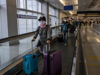 Travelers wearing face masks with suitcases crossing from Lok Ma Chau control point in Hong Kong to Futian Port in China on January 8, 2023...