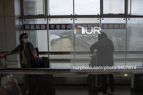 Travelers wearing face masks with suitcases crossing from Lok Ma Chau control point in Hong Kong to Futian Port in China on January 8, 2023...