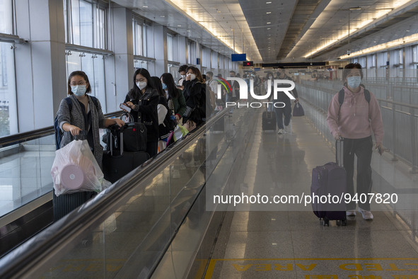 Travelers wearing face masks with suitcases crossing from Lok Ma Chau control point in Hong Kong to Futian Port in China on January 8, 2023...