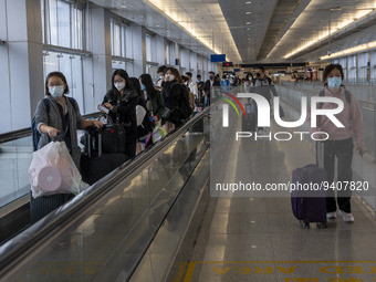 Travelers wearing face masks with suitcases crossing from Lok Ma Chau control point in Hong Kong to Futian Port in China on January 8, 2023...