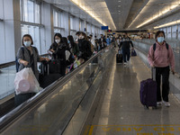 Travelers wearing face masks with suitcases crossing from Lok Ma Chau control point in Hong Kong to Futian Port in China on January 8, 2023...