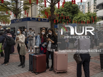 Travelers wearing face masks with suitcases outside Futian Port on January 8, 2023 in Shenzhen, China. Hong Kong today resumes quarantine fr...