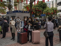 Travelers wearing face masks with suitcases outside Futian Port on January 8, 2023 in Shenzhen, China. Hong Kong today resumes quarantine fr...