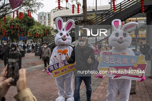 A man posing for a photo with workers dress in rabbit suits welcome visitors outside Futian Port on January 8, 2023 in Shenzhen, China. Hong...