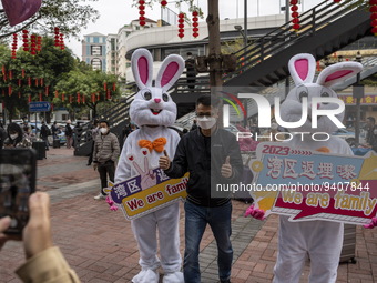 A man posing for a photo with workers dress in rabbit suits welcome visitors outside Futian Port on January 8, 2023 in Shenzhen, China. Hong...