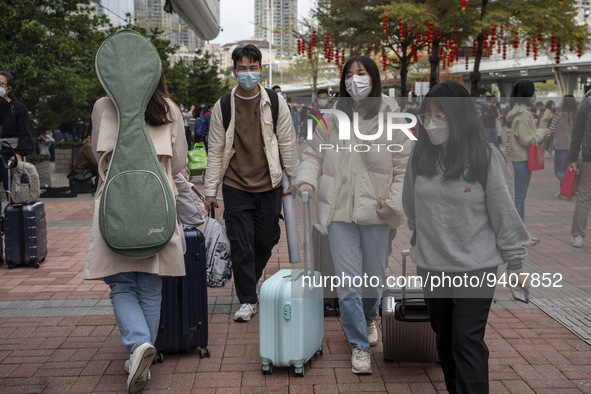 Travelers wearing face masks with suitcases outside Futian Port on January 8, 2023 in Shenzhen, China. Hong Kong today resumes quarantine fr...