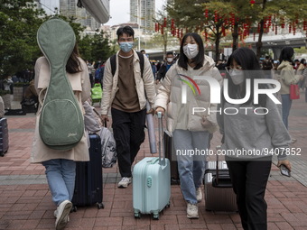 Travelers wearing face masks with suitcases outside Futian Port on January 8, 2023 in Shenzhen, China. Hong Kong today resumes quarantine fr...