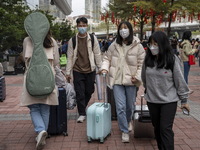 Travelers wearing face masks with suitcases outside Futian Port on January 8, 2023 in Shenzhen, China. Hong Kong today resumes quarantine fr...