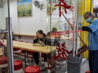 A women eating in a restaurant while a cleaner is working outside on January 8, 2023 in Shenzhen, China. China today lifts its requirement f...