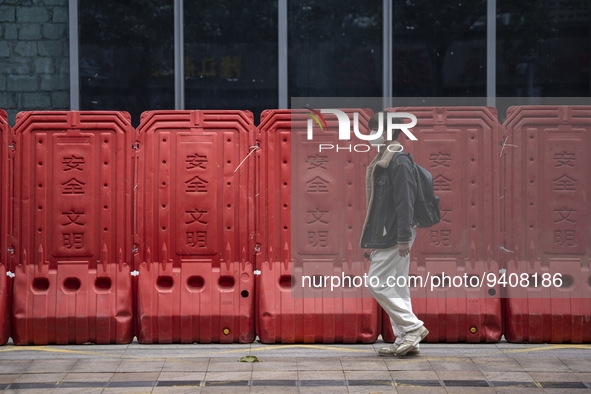 A man wearing a face mask walks pass barricades on January 8, 2023 in Shenzhen, China. China today lifts its requirement for inbound travele...