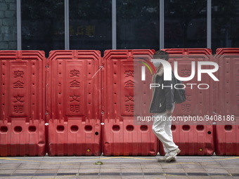 A man wearing a face mask walks pass barricades on January 8, 2023 in Shenzhen, China. China today lifts its requirement for inbound travele...