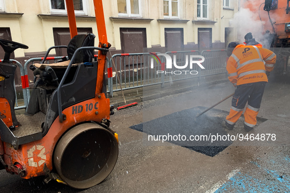 A worker patches the street with asphalt in Krakow, Poland on January 19, 2023. 