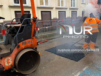 A worker patches the street with asphalt in Krakow, Poland on January 19, 2023. (