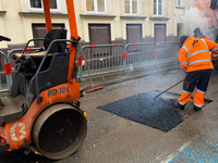 A worker patches the street with asphalt in Krakow, Poland on January 19, 2023. (