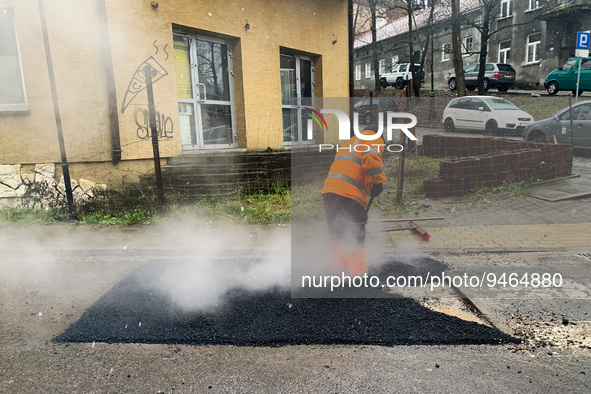 A worker patches the street with asphalt in Krakow, Poland on January 19, 2023. 