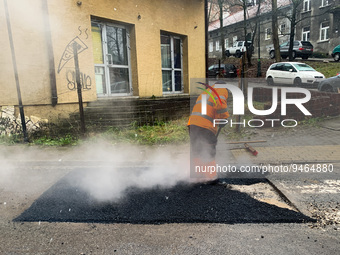 A worker patches the street with asphalt in Krakow, Poland on January 19, 2023. (