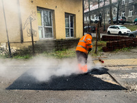 A worker patches the street with asphalt in Krakow, Poland on January 19, 2023. (