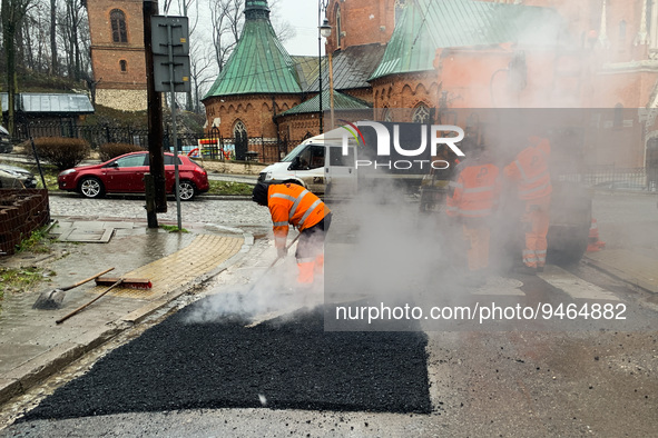 Workers patch the street with asphalt in Krakow, Poland on January 19, 2023. 