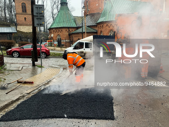 Workers patch the street with asphalt in Krakow, Poland on January 19, 2023. (