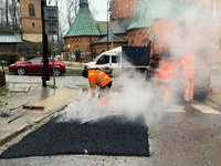 Workers patch the street with asphalt in Krakow, Poland on January 19, 2023. (